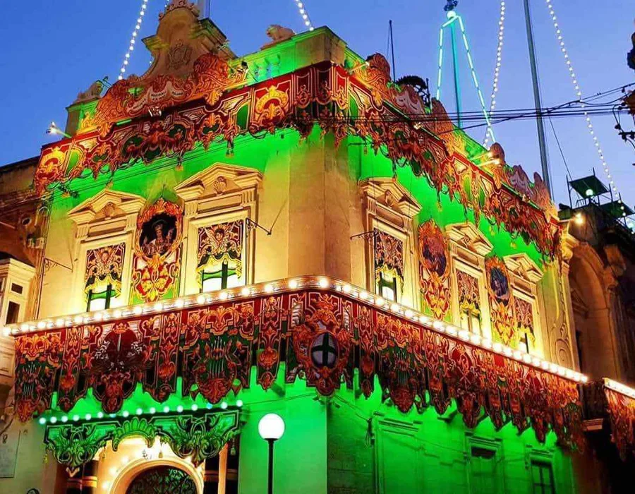 A band club front lit up for the village feast