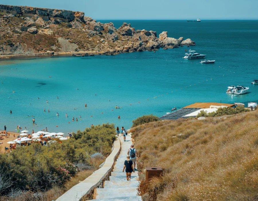 A busy Maltese bay full of swimmers and yachts at the height of summer