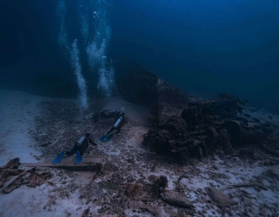 Two scuba divers exploring an underwater shipwreck