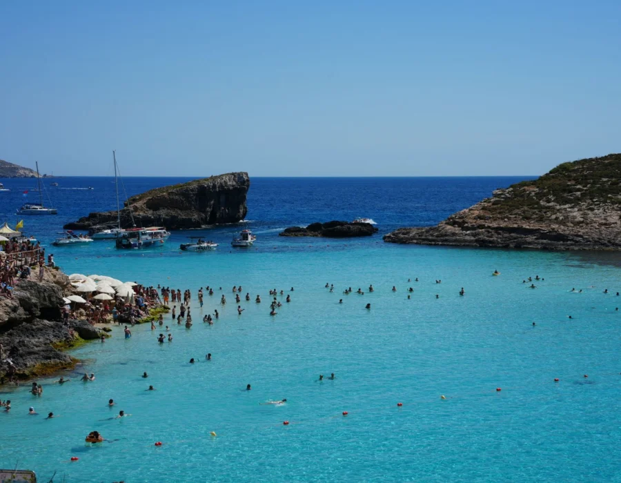 Boats and swimmers in the clear blue water of the Blue Lagoon in Comino