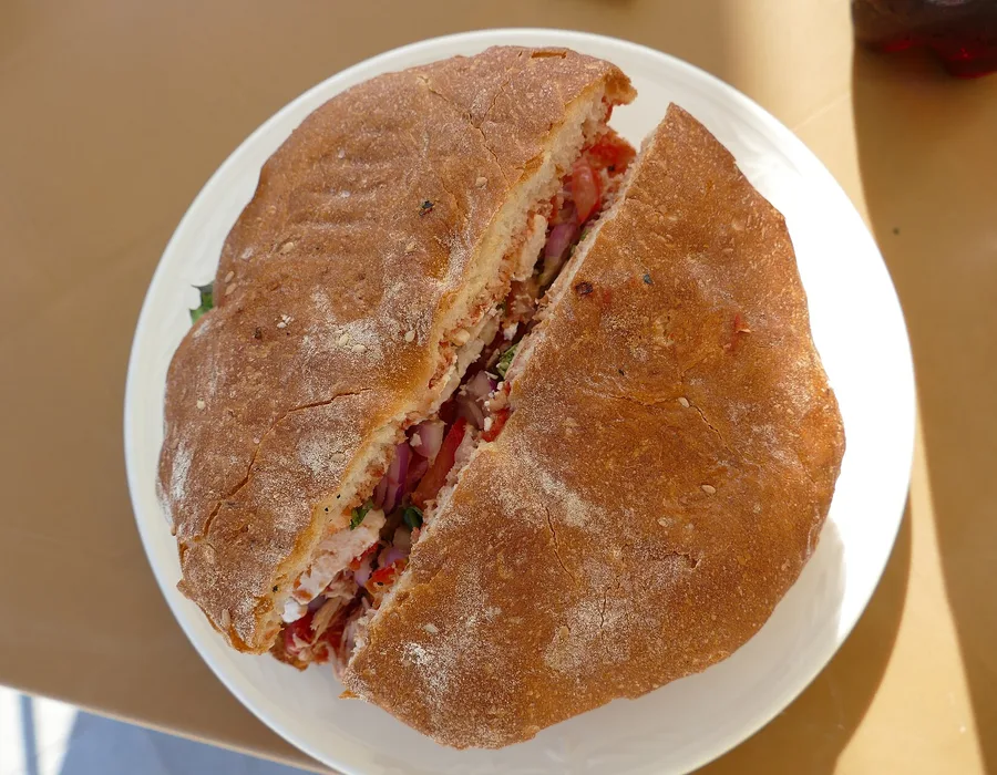A filled ftira cut in half on a plate