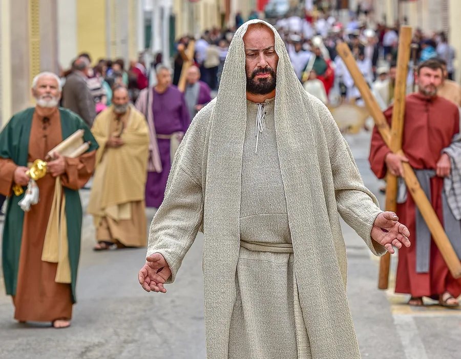Costumed figures in a Good Friday procession through a Maltese village