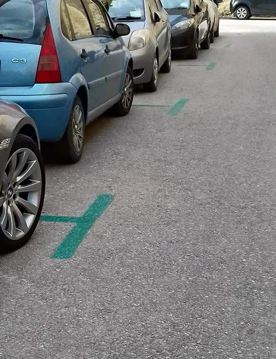 Painted parking bays on a Maltese street, showing the colours that mark who may park