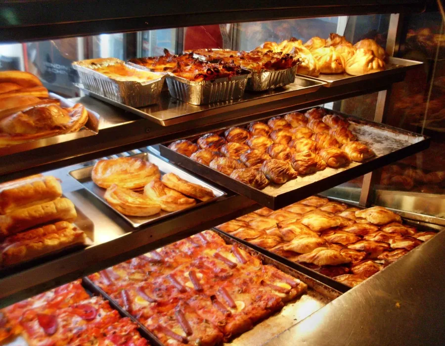 A pastizzeria display case with pastizzi, pies and pizza