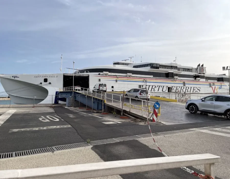 A Virtu Ferries catamaran with its ramp down and a car driving aboard