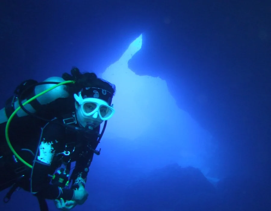 A scuba diver exploring a bright blue underwater cave