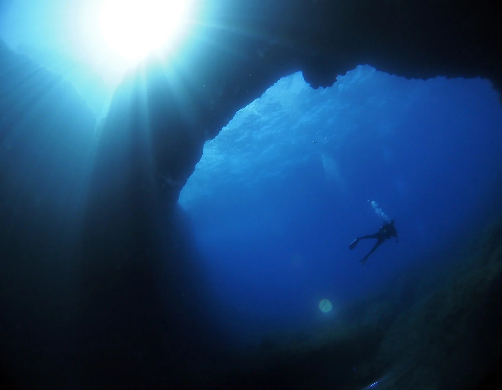 A diver in the cavern at the Blue Hole, Dwejra, with sunlight through the opening